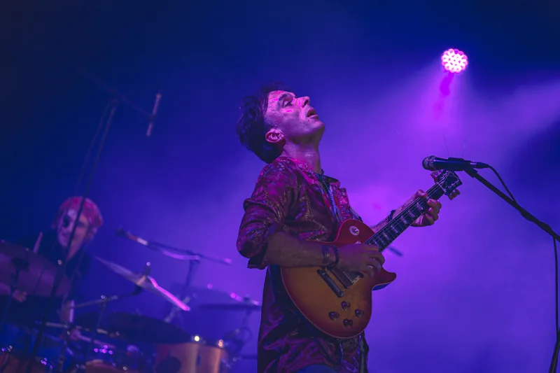 Musicien et guitare électrique dans une lumière violette de scène