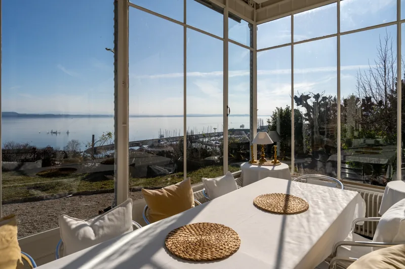 Table préparée près de grandes baies vitrées ouvertes sur le paysage
