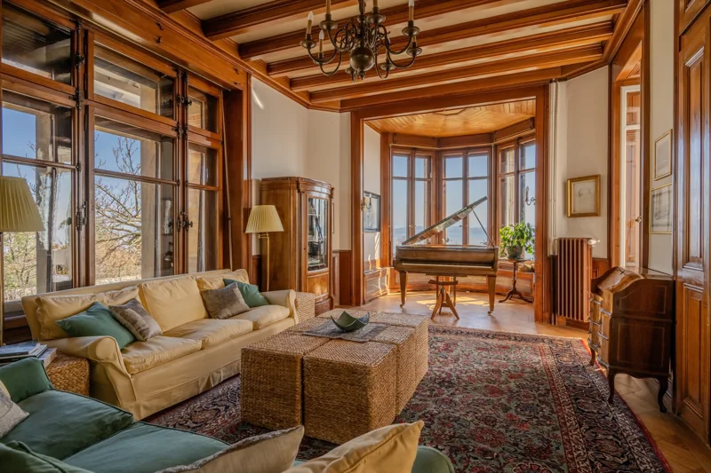 Salon chaleureux avec boiseries, fauteuils et grandes fenêtres