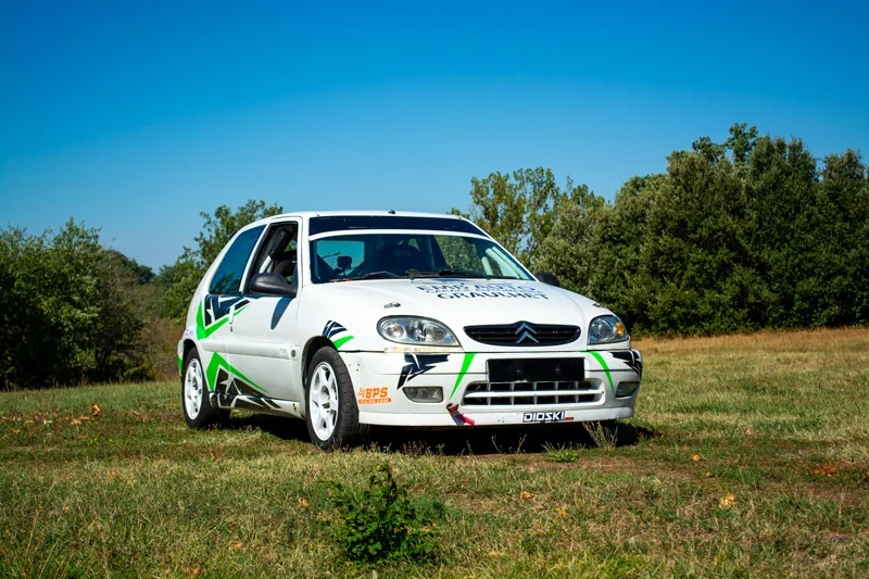 Voiture de rallye photographiée dans un pré sous un ciel bleu
